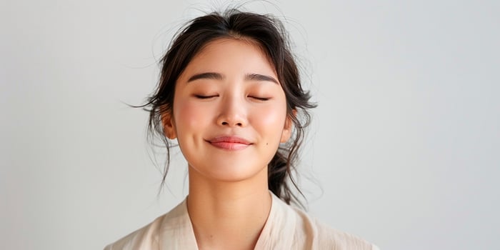 AI generated Portrait of a happy romantic Asian woman waiting for a surprise, with eyes closed and smiling isolated on light background photo
