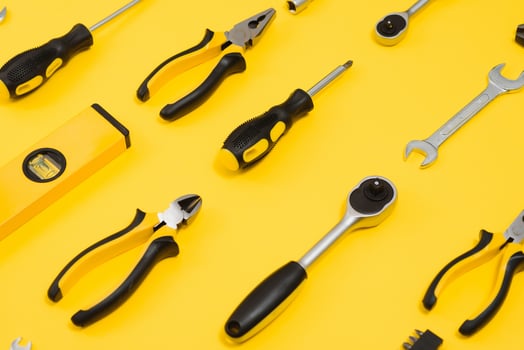 Yellow and black handy tools pilers and screwdriver isolated on yellow background. photo