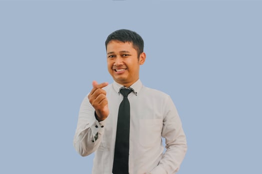 Adult Asian man smiling happy while making sarangheyo pose with his hands photo