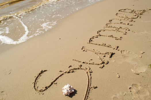 The word summer is written on the sand by hand. photo