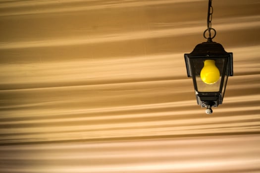 The yellow bulb in the black lantern on the ceiling. Close up. photo