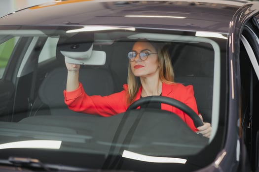 young woman looking in the rearview mirror of a car photo