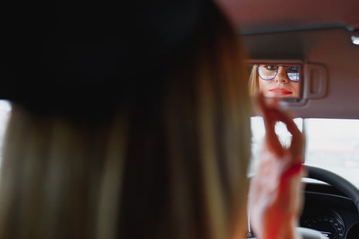 young woman looking in the rearview mirror of a car photo