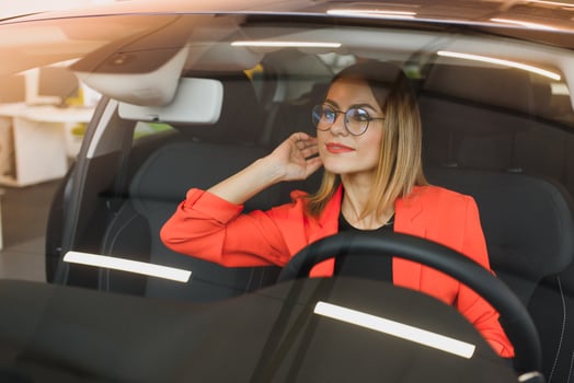 young woman looking in the rearview mirror of a car photo