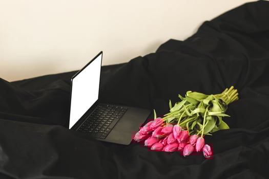 A bouquet of pink flowers on black stylish linen with an open laptop. photo