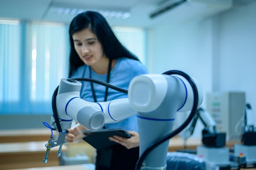 Female Robotics engineer working with Programming and Manipulating Robot Hand, Industrial Robotics Design, High Tech Facility, Modern Machine Learning. Mass Production Automatics. photo
