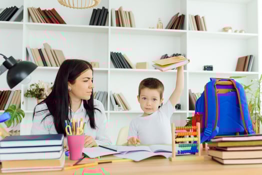 Female private tutor helping young student with homework at desk in bright child's room photo