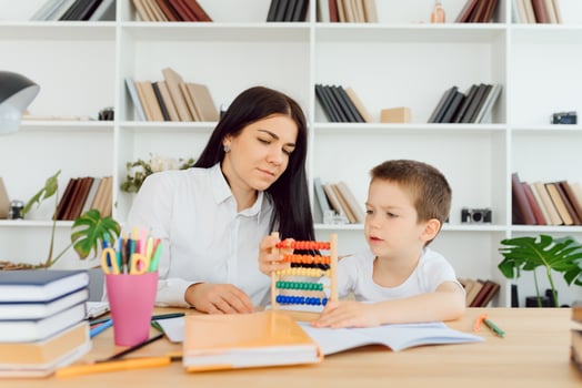 Female private tutor helping young student with homework at desk in bright child's room photo