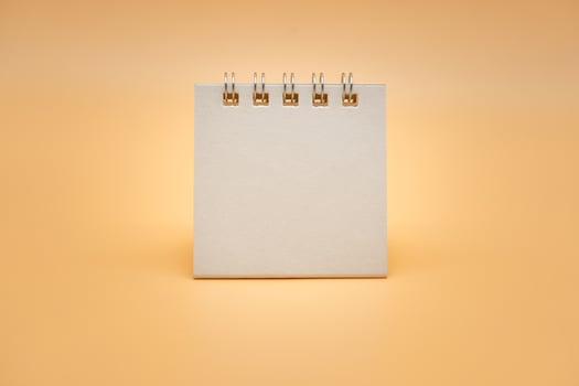 Blank calendar isolated on orange background. Blank paper desk spiral calendar. close up of a blank recycle paper template. photo