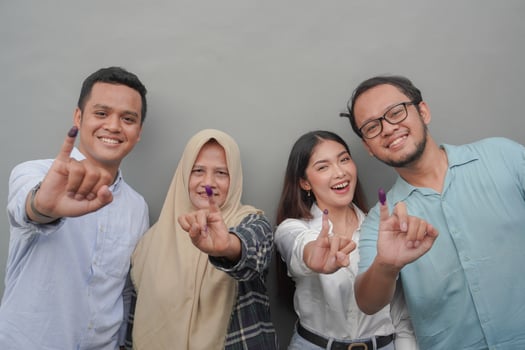 Portrait of excited Indonesian family showing the little finger dipped in purple ink after voting for general election or Pemilu for president and government, isolated grey background photo