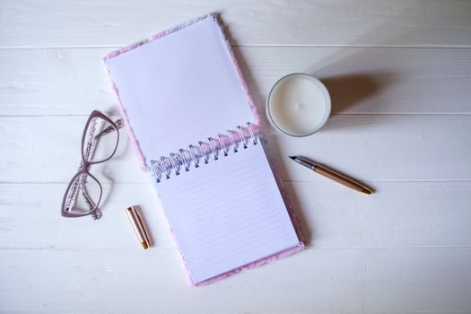 The opened notepad, pen, white candle, glasses and branches of hops as decoration on a white wooden table. Desktop still life with space for text. photo