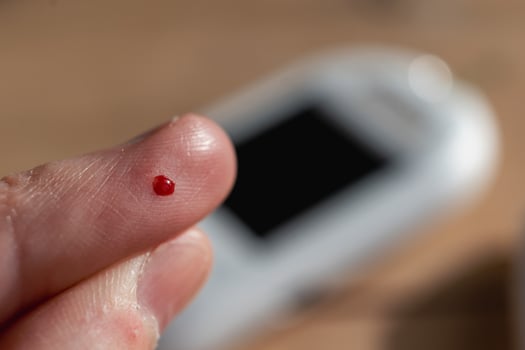 Woman pricking her finger to check blood glucose level with glucometer, test blood glucose for diabetes photo