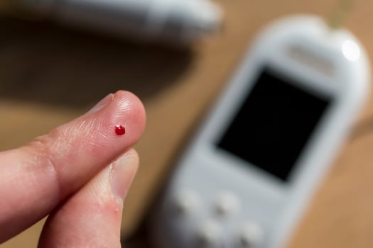 Woman pricking her finger to check blood glucose level with glucometer, test blood glucose for diabetes photo