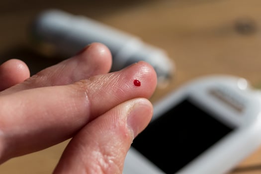 Woman pricking her finger to check blood glucose level with glucometer, test blood glucose for diabetes photo