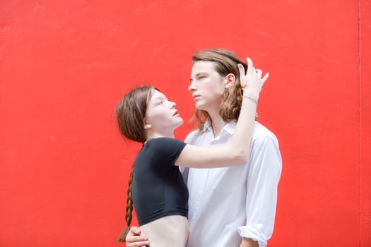 A couple is enjoying a summer vacation in the red wall background, happily showing their love to each other. photo