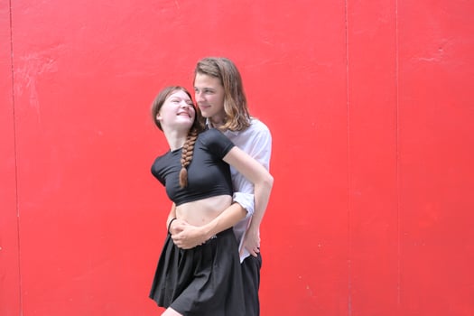 A couple is enjoying a summer vacation in the red wall background, happily showing their love to each other. photo