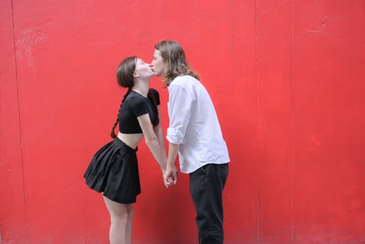 A couple is enjoying a summer vacation in the red wall background, happily showing their love to each other. photo