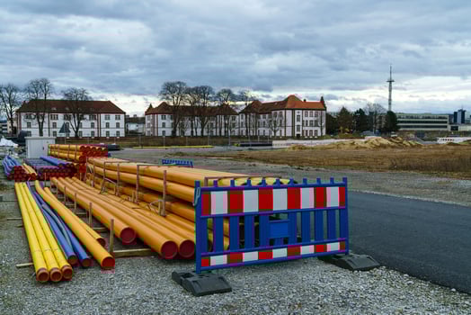 Plastic orange and blue pipes and a portable barrier lie on a construction site. photo