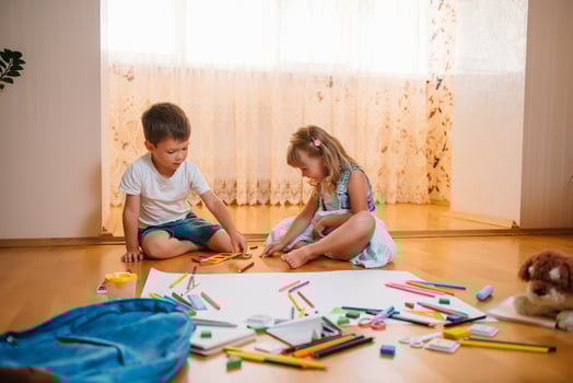 Kids drawing on floor on paper. Preschool boy and girl play on floor with educational toys - blocks, train, railroad, plane. Toys for preschool and kindergarten. Children at home or daycare photo