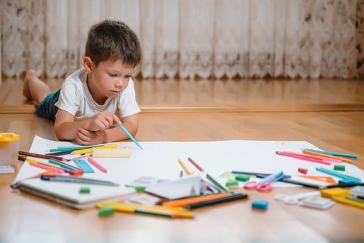 Kids drawing on floor on paper. Preschool boy and girl play on floor with educational toys - blocks, train, railroad, plane. Toys for preschool and kindergarten. Children at home or daycare. photo