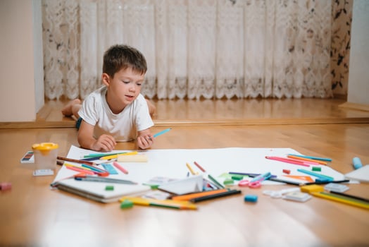 Kids drawing on floor on paper. Preschool boy and girl play on floor with educational toys - blocks, train, railroad, plane. Toys for preschool and kindergarten. Children at home or daycare. photo