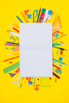 School notebook and stationery over yellow desk. Back to school abstract background. School equipment. Variety of school supplies. Flat lay photo