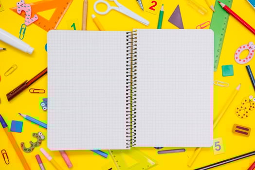 School notebook and stationery over yellow desk. Back to school abstract background. School equipment. Variety of school supplies. Flat lay photo