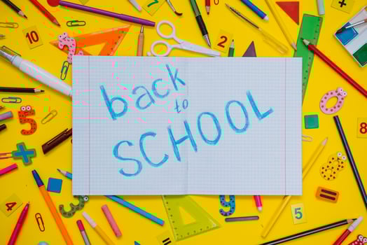 School notebook and stationery over yellow desk. Back to school abstract background. School equipment. Variety of school supplies. Flat lay photo