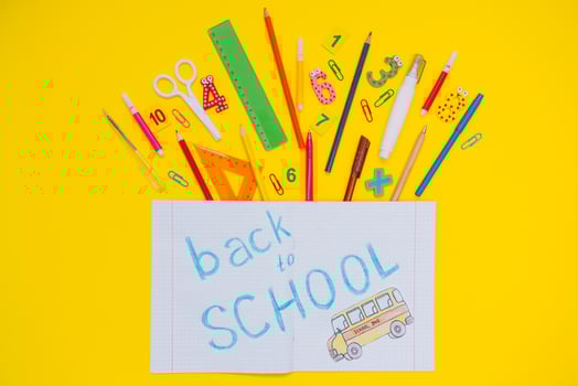 School notebook and stationery over yellow desk. Back to school abstract background. School equipment. Variety of school supplies. Flat lay photo