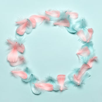 Happy easter greeting card template. Round frame made of colorful feathers on pastel blue background. Flat lay, copy space photo