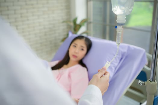 Female doctor with IV equipment will give IV fluids and examine patients lying in hospital beds photo