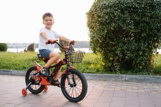 children on a bicycle at asphalt road in early morning. Little boy learns to ride a bike in the park. Happy smiling child, riding a cycling photo