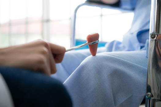 A doctor uses a reflex hammer to evaluate a patient's knee joint photo