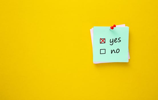 Ticking Yes. Sticky note with red push pin on yellow background. photo
