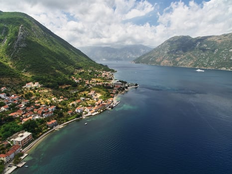 Resort town among green trees on a mountainside by the sea. Dobrota, Montenegro. Drone photo