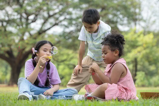 Children sitting in the park with blowing air bubble, Surrounded by greenery and nature photo