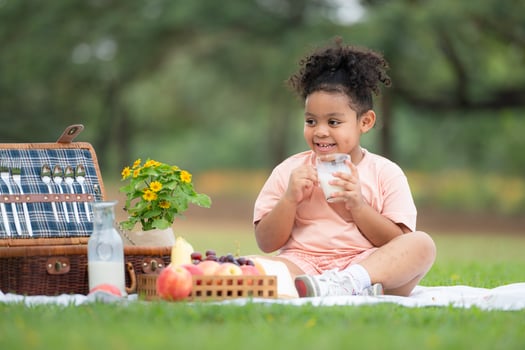 Happy family enjoying a picnic in the park, with kids drinking  milk, surrounded by nature photo