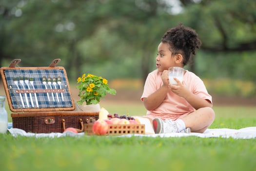 Happy family enjoying a picnic in the park, with kids drinking  milk, surrounded by nature photo