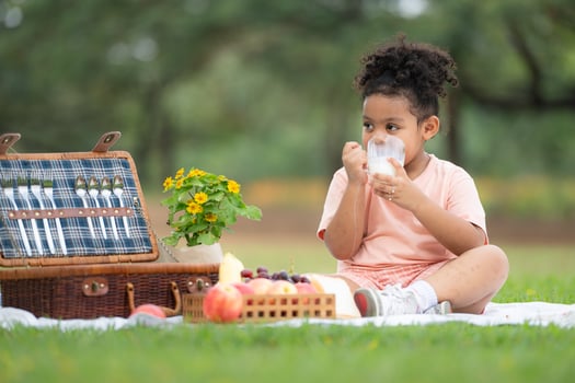 Happy family enjoying a picnic in the park, with kids drinking  milk, surrounded by nature photo