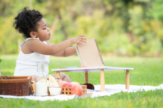 Happy family enjoying a picnic in the park, Girl are having fun drawing on paper placed on the table. photo