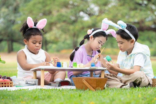 Happy family enjoying a picnic in the park, Children sitting and coloring their beautiful Easter eggs. photo