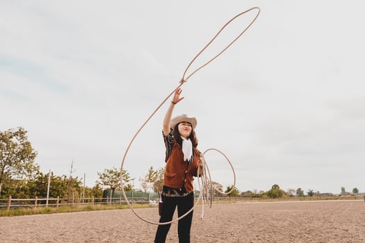 pretty Chinese cowgirl throwing the lasso in a horse paddock photo
