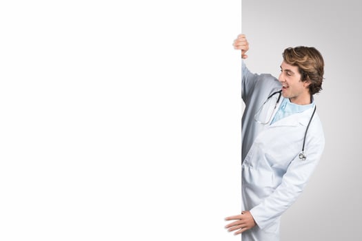 Happy man doctor holding blank white board, inviting questions photo