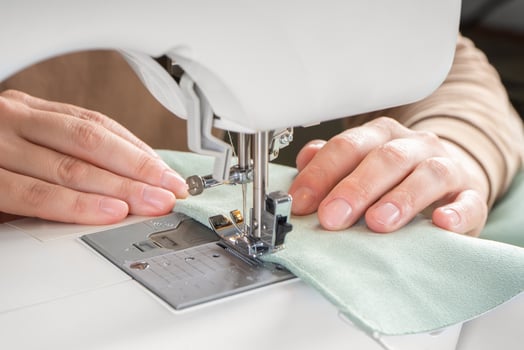 Female hands stitching green fabric on modern sewing machine at workplace in atelier photo