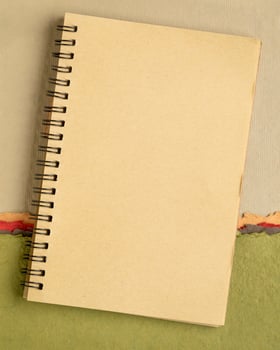 blank spiral sketchbook against colorful abstract paper landscape photo