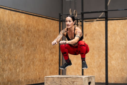 Strong sportive woman jumping into box in a gym photo