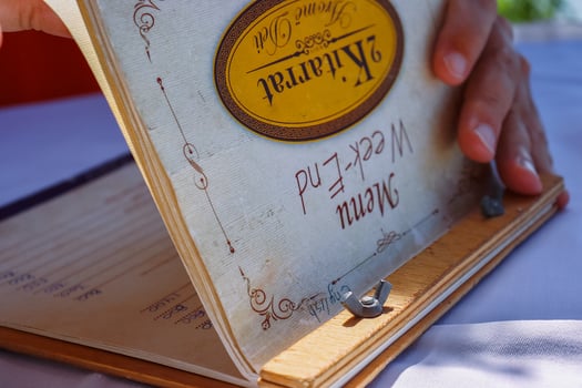 Durres, Albania. September 3rd 2022. Restaurant 2 Kitarrat Arome Deti. Man holding and reading the menu card, choosing the meal. Beautiful restaurant on Adriatic sea beach on a sunny day. photo