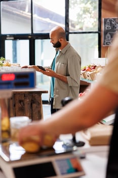 An Arab male customer browsing on the internet while looking at a certain section in an environmentally friendly grocery store. Modern technology being utilized in a sustainable supermarket. photo