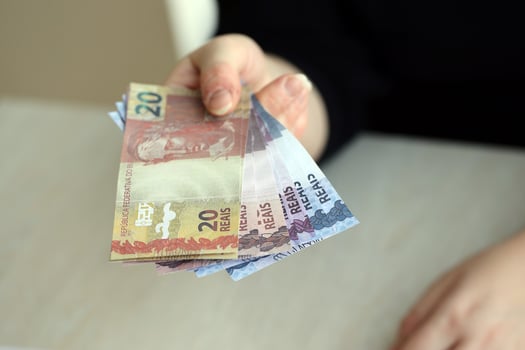 Brazilian money bills in woman hand. Female gives bunch of brazilian reais to us photo