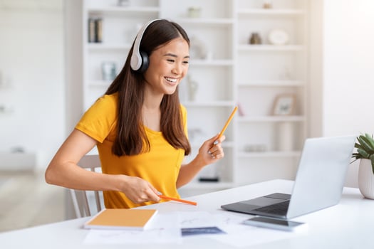 Cheerful Asian Woman Wearing Headphones Having Fun While Using Laptop photo